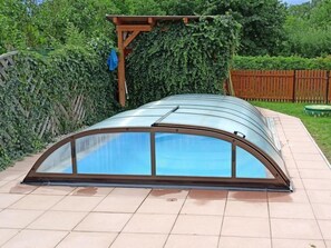 A greenhouse structure with a curved glass roof and wooden support beams.