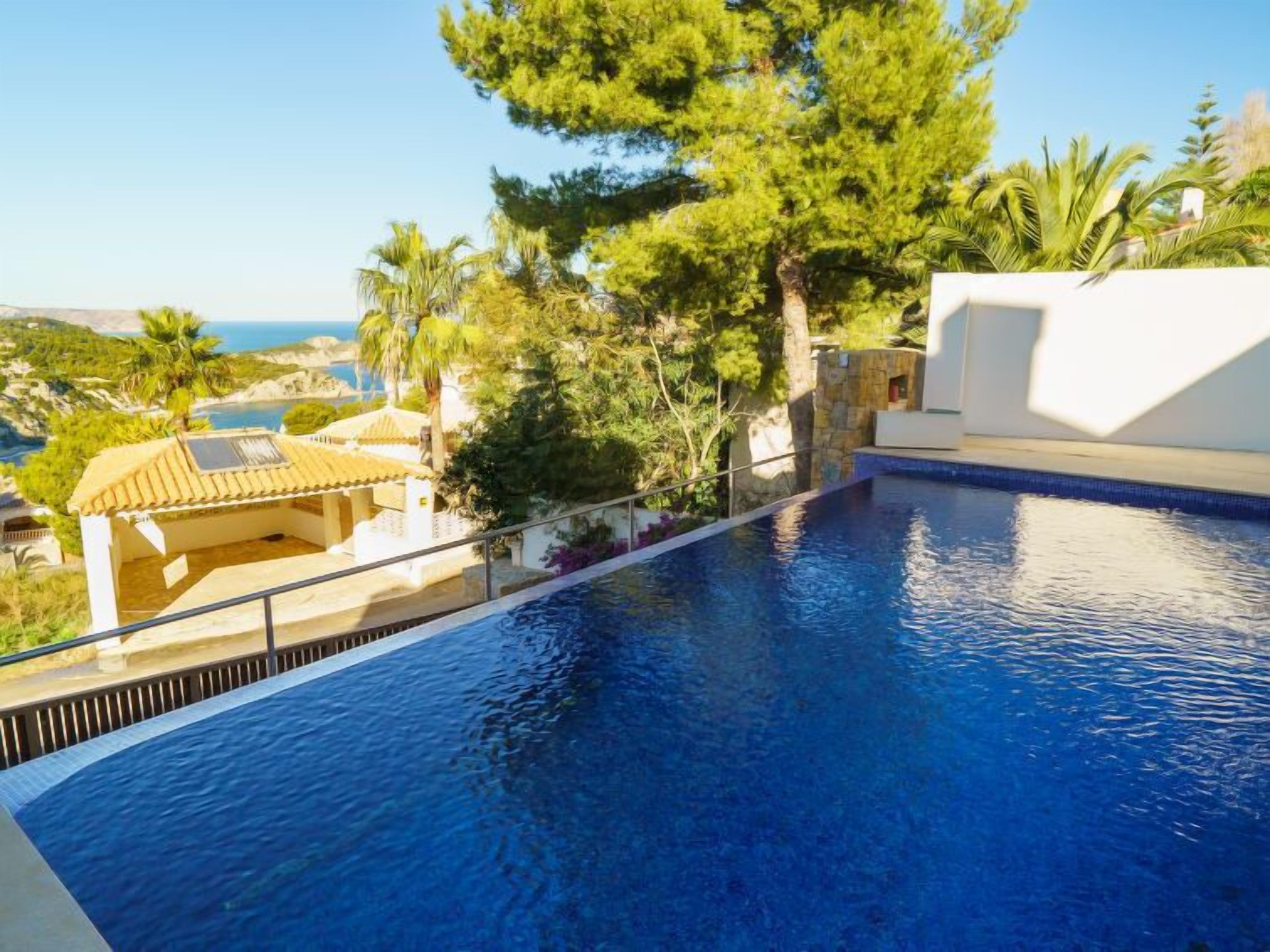 A swimming pool with a clear view of the sea and surrounding greenery.