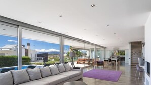 A modern living room with a large sofa, a coffee table, and a dining area with chairs and a table. - Villa Vogue by Interhome (Ferragudo)