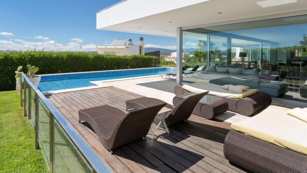 A modern outdoor pool area with lounge chairs and a glass-enclosed living space. - Villa Vogue by Interhome (Ferragudo)