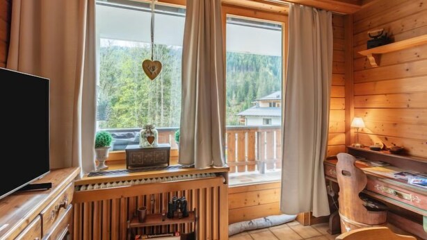 Une cabane en bois équipée d’une télévision, d’un bureau en bois et offrant une vue sur une zone boisée.