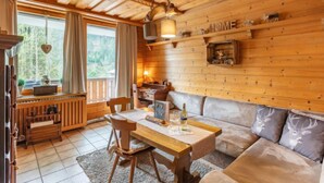 L’intérieur d’un chalet chaleureux, avec une table à manger en bois, un canapé et une cheminée.