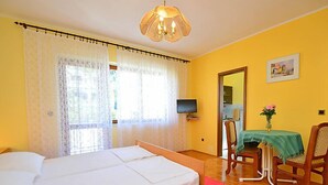 Quarto com uma cama, televisão, mesa com um vaso de flores e uma cadeira.