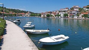 Uma marina com vários barcos pequenos atracados ao longo de uma passarela de concreto, rodeada por edifícios residenciais com telhados de telha vermelha.