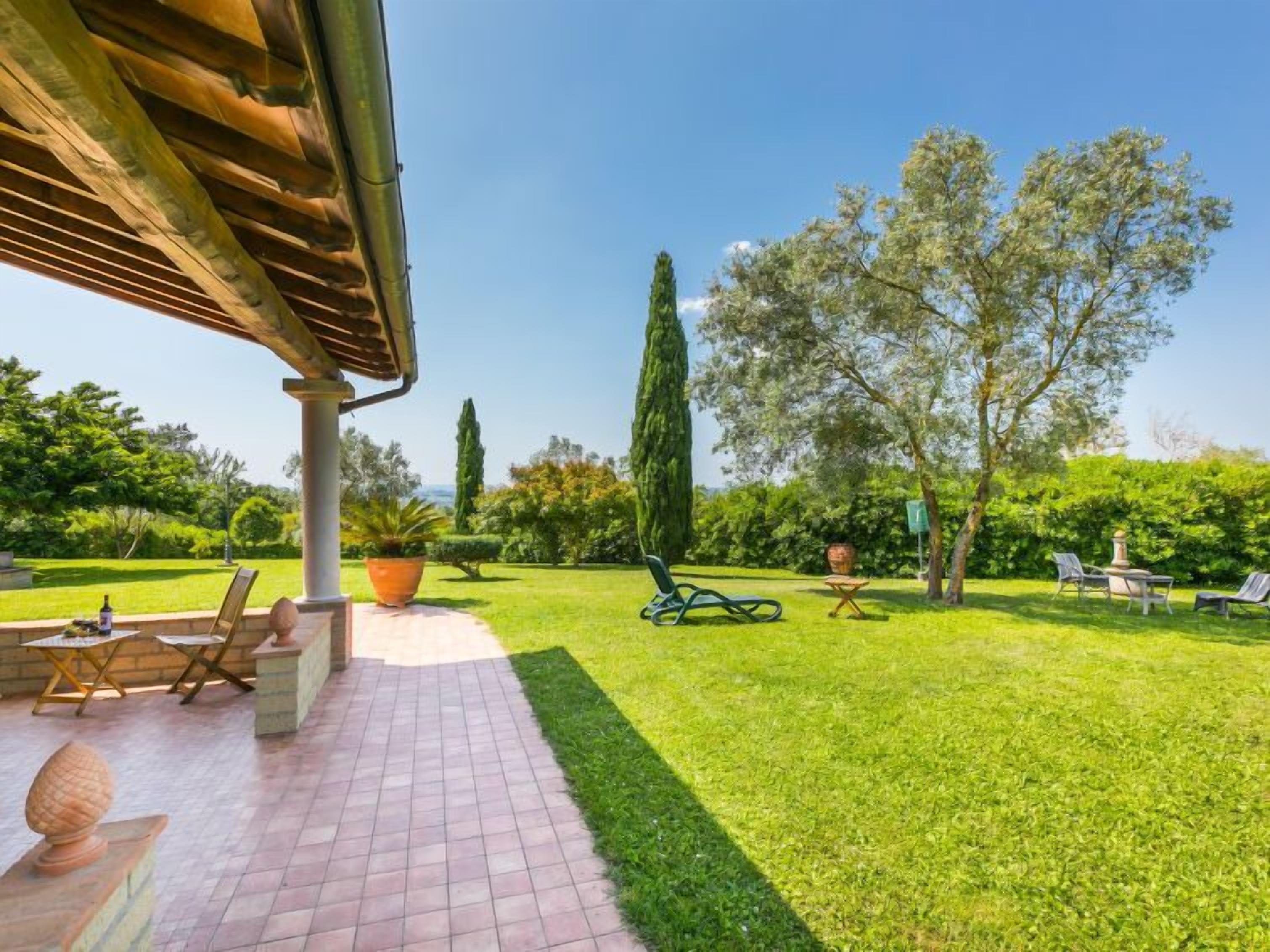 A patio area with a pergola, outdoor seating, and a well-maintained lawn.