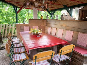 Ein Holztisch mit Bänken, einer roten Tischdecke und einer floralen Tischdekoration.