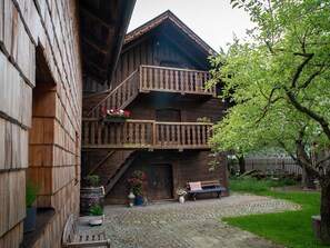 Ein hölzernes Gebäude mit Balkon, Bank und Blumentöpfen.