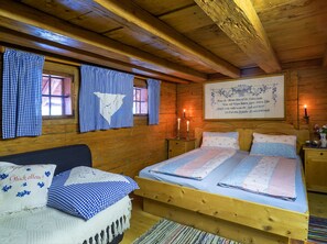Ein gemütliches Holzhütten-Zimmer mit Bett, Nachttisch und einem an der Wand hängenden Bild.