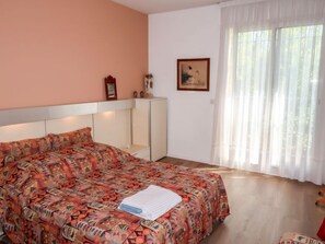 A bedroom with a bed, a wardrobe, a painting, and a window with curtains. - La Cigale by Interhome (Avignon)