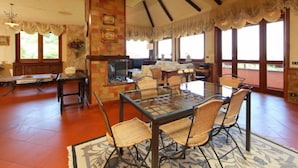 A spacious dining area with a glass table and wicker chairs, a fireplace, and large windows offering natural light. - Villa Mina by Interhome (Frascati)