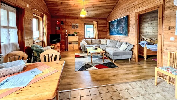 A cozy cabin interior with wooden walls, a sofa, a TV, and a dining area. - Löwenzahn by Interhome (Adenau)