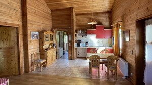 A wooden cabin interior with a dining area, kitchen, and a hallway leading to another room. - Löwenzahn by Interhome (Adenau)