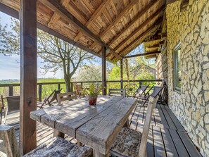 A wooden deck with a rustic stone wall, wooden furniture, and a view of the countryside. - Moja Mała Toskania by Interhome (Cisowa)
