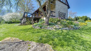 A rustic stone building with a wooden staircase leading to a deck, surrounded by a well-maintained garden with various plants and flowers. - Moja Mała Toskania by Interhome (Cisowa)