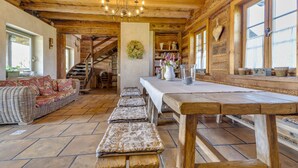 A rustic wooden interior with a long dining table, benches, and a wicker sofa. - Moja Mała Toskania by Interhome (Cisowa)