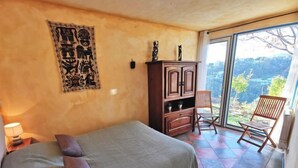 A bedroom with a bed, a wooden cabinet, a chair, and a view of the outdoors. - Vacation home Agora by Interhome (Nice)