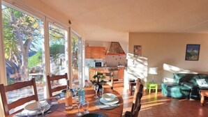 A dining area with a table set for four, a kitchen in the background, and a green sofa in the living area. - Vacation home Agora by Interhome (Nice)