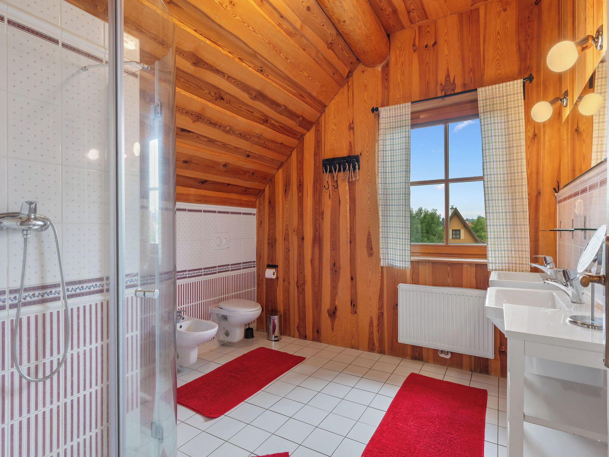 Un baño de cabaña de madera con ducha, inodoro y lavamanos.