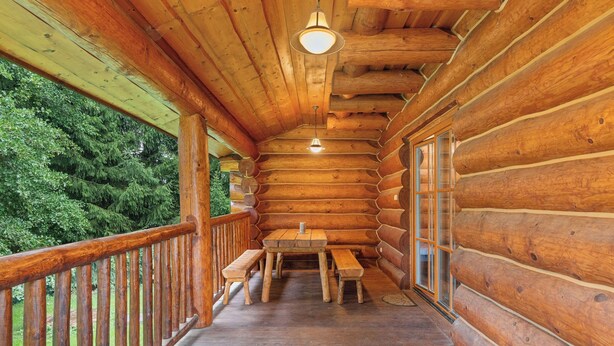 Una baita di legno con veranda, tavolo e panche.