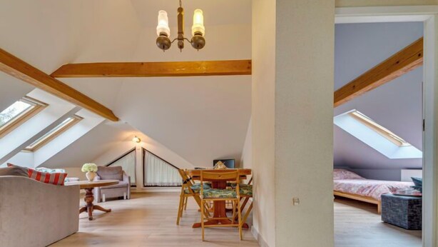 A spacious attic bedroom with skylights, a wooden ceiling, and a cozy seating area with a sofa and table. - Kubaczka by Interhome (Wisla)