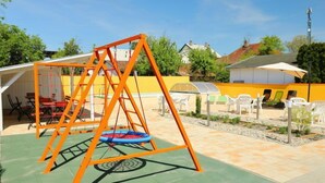 An outdoor play area with a swing set and a trampoline.