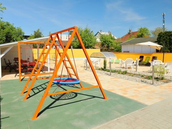 Un espace de jeux extérieur avec des balançoires et un trampoline.
