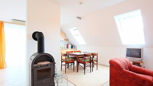A cozy living room with a fireplace, a dining area, and a television.