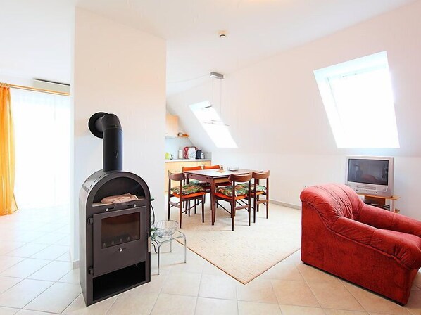 Ein gemütliches Wohnzimmer mit Kamin, Essbereich und Fernseher.