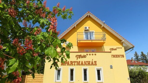 A yellow building with the sign "Terez Apartmanhaz" and a balcony.