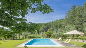 A rectangular swimming pool surrounded by a grassy lawn, with two lounge chairs and a single umbrella. - I Noccioli by Interhome (Rufina)
