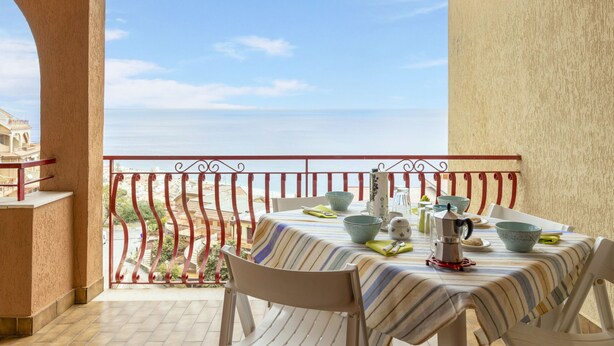 Un balcon avec une table dressée pour le dîner, offrant une vue sur la côte.