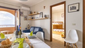 Un coin repas avec une table dressée pour deux personnes, un canapé et, au fond, un lit superposé.