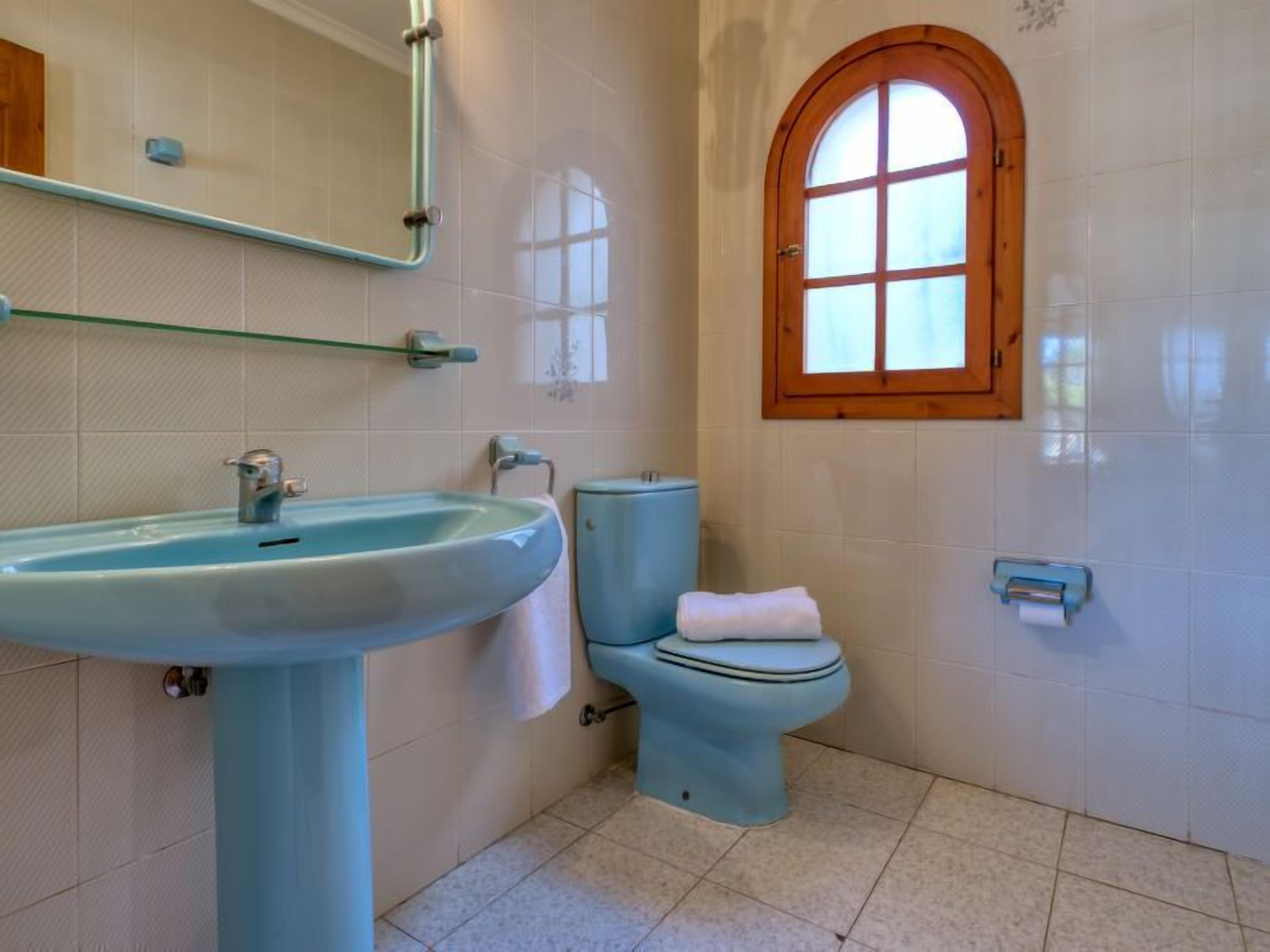 Ein Badezimmer mit Waschbecken, Toilette und einem Fenster.