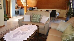 Una sala de estar acogedora con un sofá, una mesa de centro y un comedor al fondo.