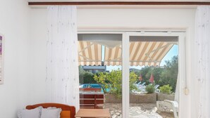 Una habitación con cama, una mesita y un ventanal corredizo que da a un espacio exterior con piscina y sombrillas.