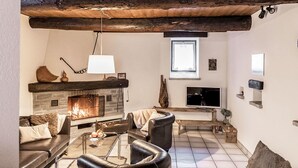 Una sala de estar acogedora con chimenea, muebles de cuero y un revestimiento de piedra alrededor de la chimenea.