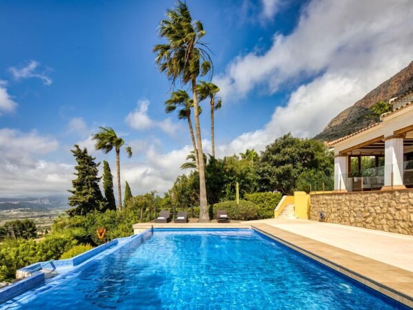 A swimming pool with a view of palm trees and a mountain in the background.