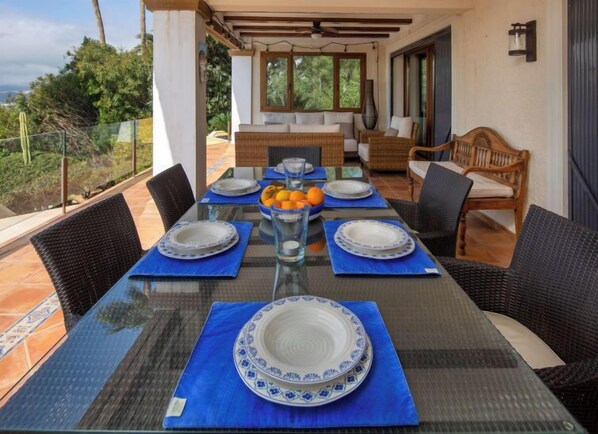 A dining area with a glass table set for four, surrounded by wicker chairs.