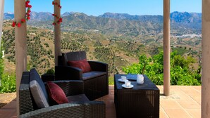 A patio with wicker furniture and a laptop, overlooking a mountainous landscape. - Villa Montemar by Interhome (Nerja)
