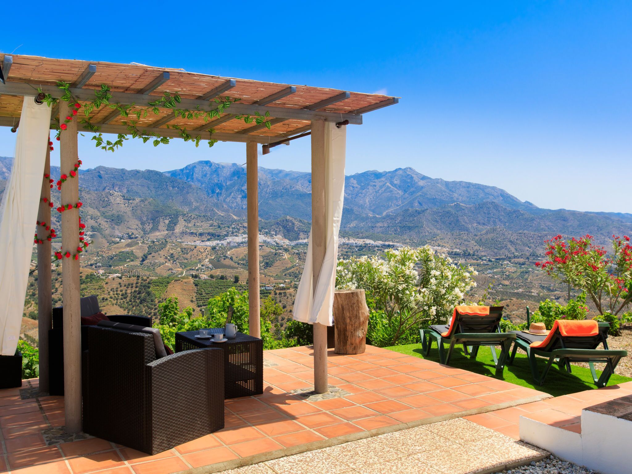 A covered outdoor seating area with wicker furniture and a view of mountains.