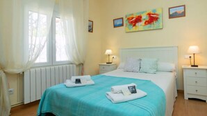A hotel room with a bed, two bedside tables with lamps, a window with curtains, and artwork on the wall. - Vacation home Pedro by Interhome (Albir)