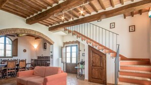 Amplia sala de estar con escalera de madera, un sofá y una mesa de comedor.