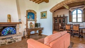 Una sala de estar acogedora con chimenea de piedra, vigas de madera y un ventanal grande.