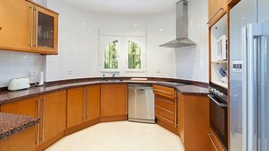 Una cocina moderna con armarios de madera, lavavajillas de acero inoxidable y horno empotrado.