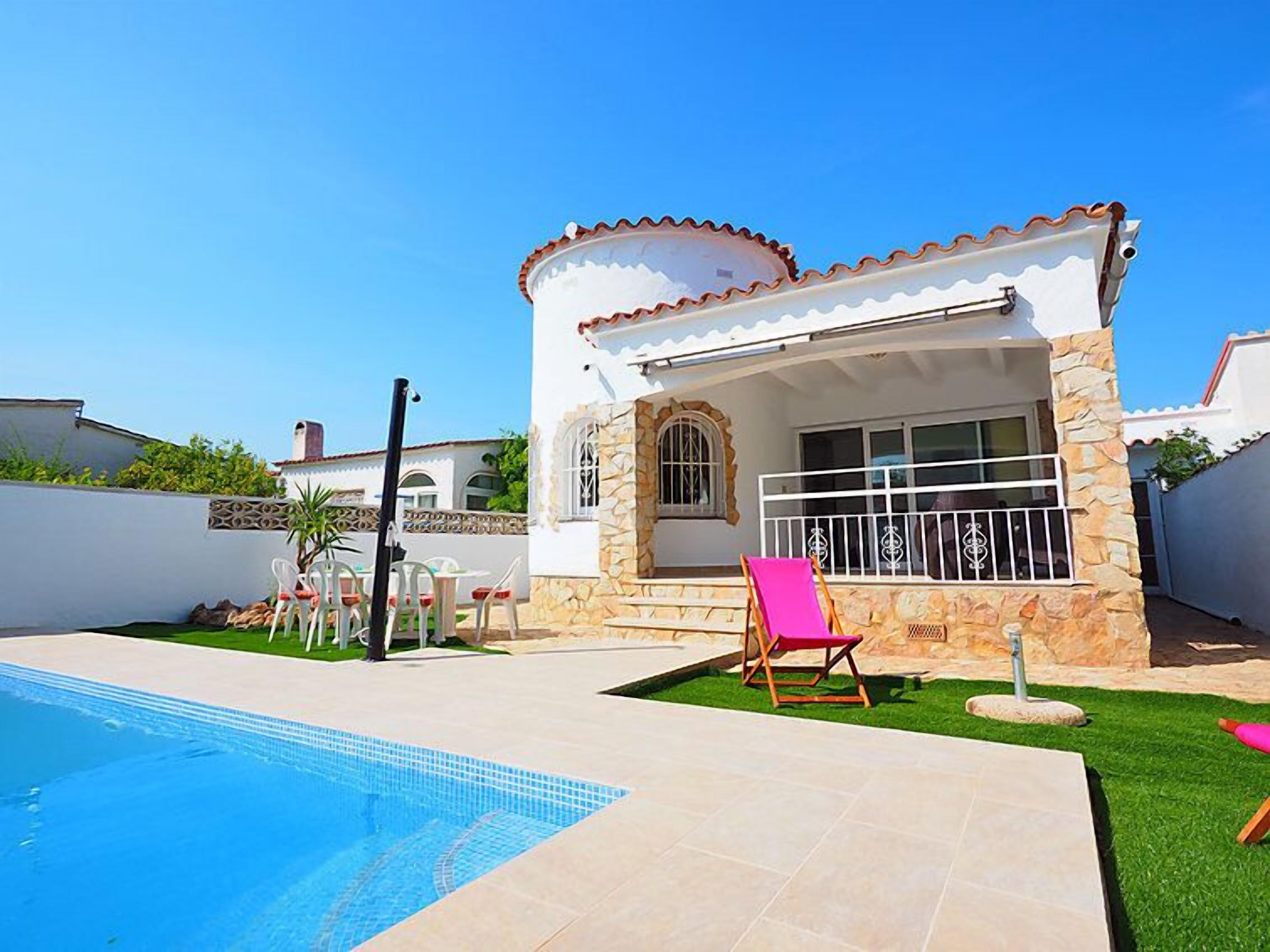 A two-story house with a swimming pool, stone exterior, and a patio with a chair.