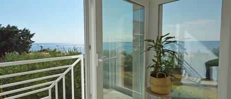 A balcony with a clear view of the sea and a potted plant.