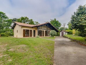 A two-story house with a sloped roof, a small attached garage, and a paved driveway.