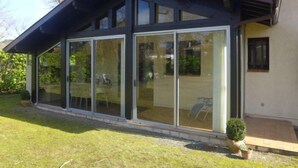 A modern house with large sliding glass doors, a sloped roof, and a small porch with potted plants. - Mauriac by Interhome (Capbreton)