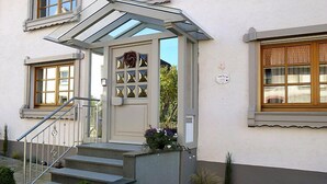 Un edificio con facciata bianca, una porta in vetro con decorazioni e una scala che conduce all'ingresso.