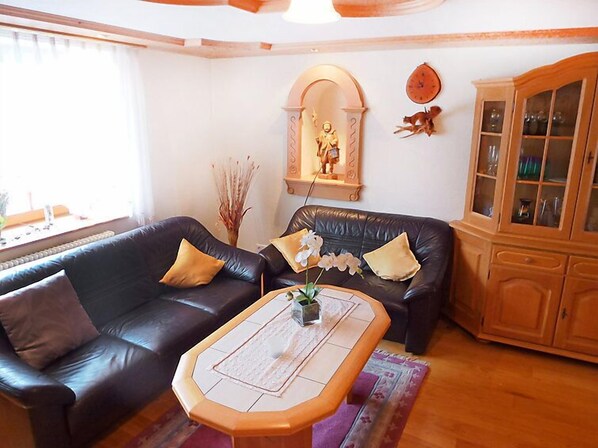 A living room with a black leather sofa, a wooden coffee table, and a cabinet with glass doors.